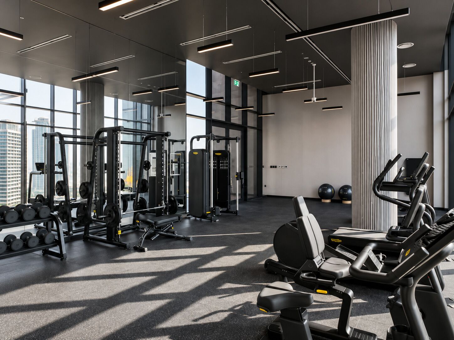 A modern gym with various exercise equipment, large windows, and a clean, minimalist design.