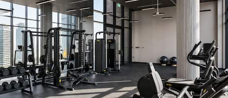 Un gimnasio moderno con equipo de ejercicio variado, amplias ventanas y un diseño limpio y minimalista.