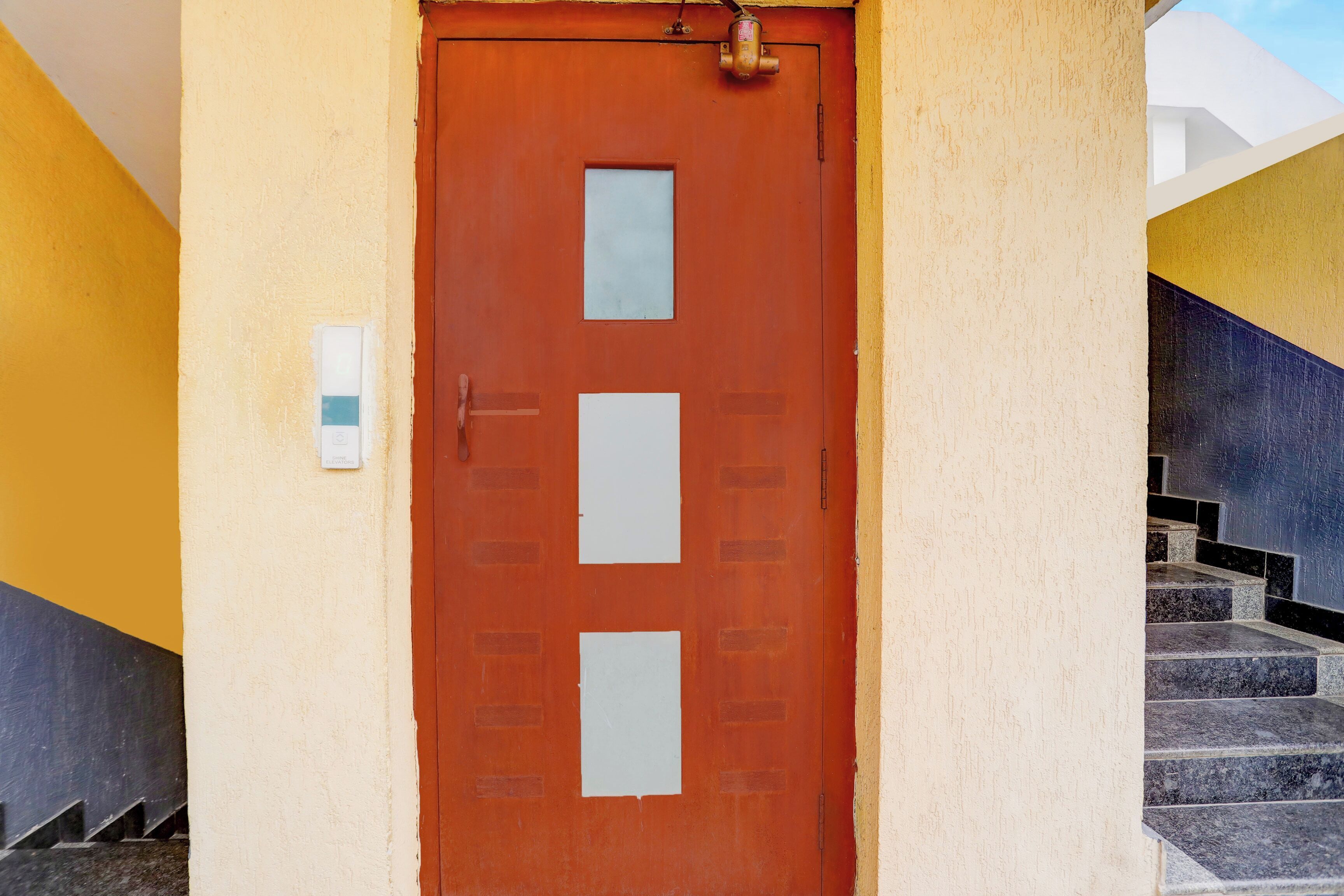 Una puerta roja con una pequeña ventana y un timbre.