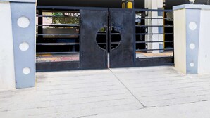 Una entrada cerrada con un portón metálico que tiene cortes circulares y un ventanal circular en el centro.