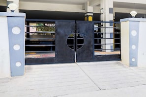 Una entrada cerrada con un portón metálico que tiene cortes circulares y un ventanal circular en el centro.