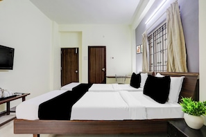 Una habitación de hotel con cama, mesita de noche y televisor.