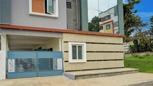Un edificio residencial con puerta de garaje, una pequeña ventana y un sendero de hormigón que lleva a la entrada.