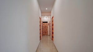 Un pasillo estrecho y bien iluminado con suelo de baldosas que conduce a una puerta con un diseño en forma de V.