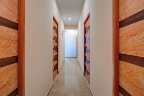 A corridor with wooden doors and a tiled floor. - Collection O Biocon Hebbagodi (Bengaluru)