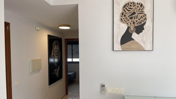 Un pasillo con un cuadro enmarcado que muestra el perfil de una mujer, una puerta y un interruptor de luz en la pared.