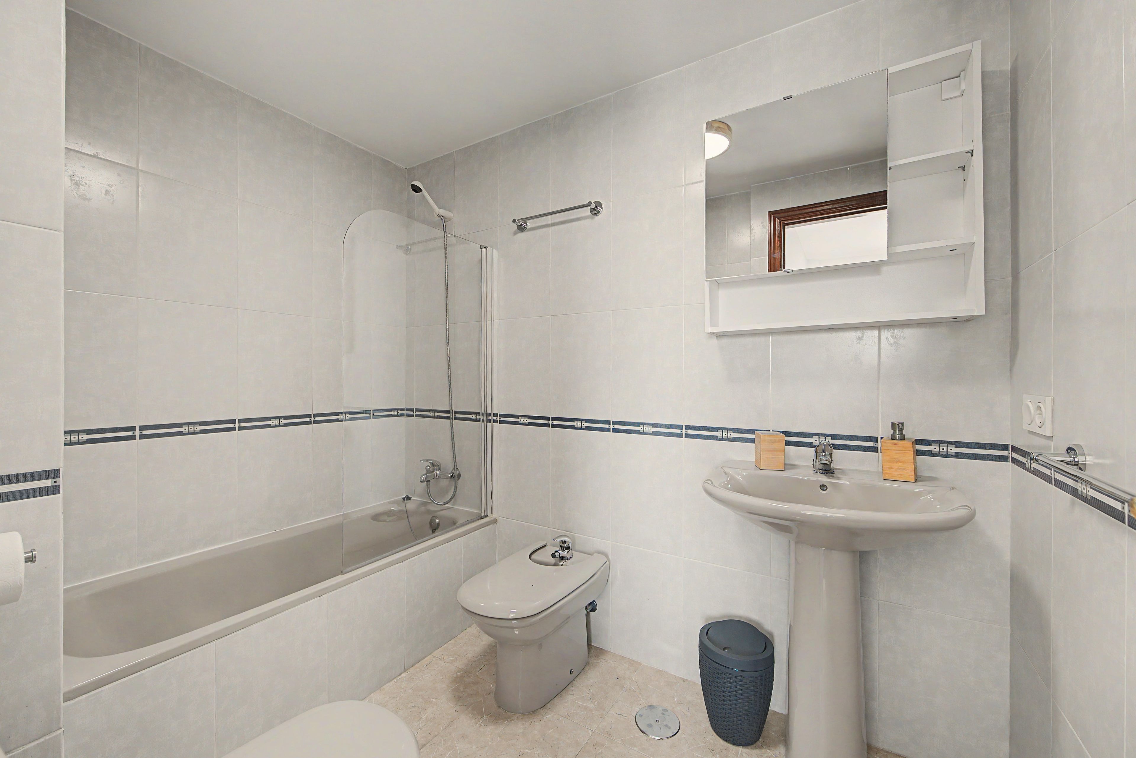 A bathroom with a bathtub, toilet, sink, and a mirror.