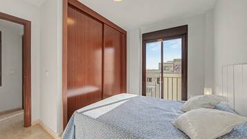 Une chambre à coucher avec un lit, une armoire en bois et une porte-fenêtre donnant sur un balcon.
