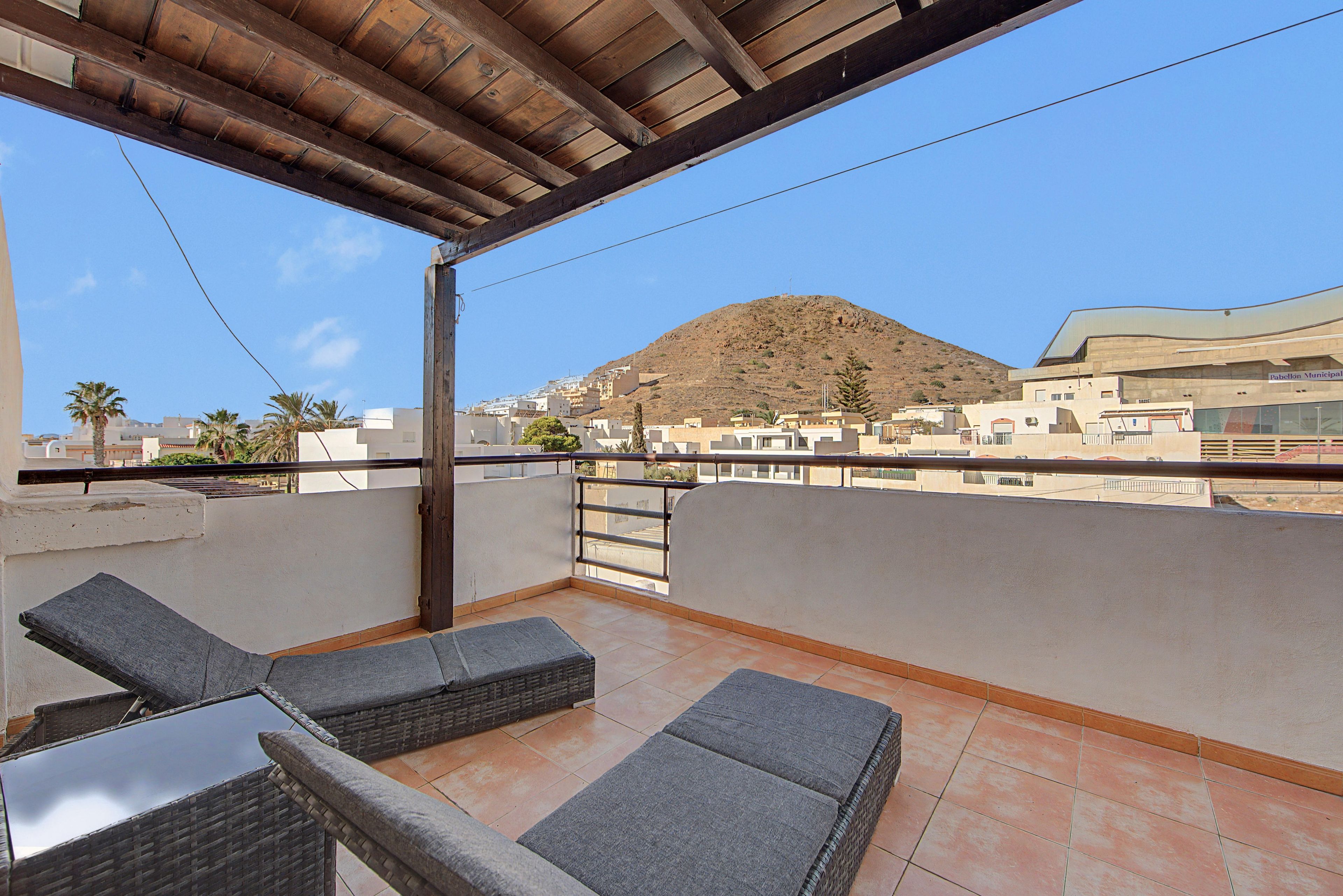 A balcony with wicker furniture and a view of a hillside town.