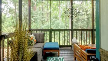 A covered outdoor seating area with a sofa, a small table, and a bench.