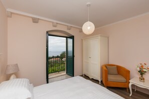 A bedroom with a bed, a chair, a nightstand, a wardrobe, and a balcony with a view. - Apartment&rooms Savonari - Superior Double Room With Balcony and Sea View (Dubrovnik)