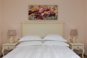 A bed with white bedding, two bedside tables with lamps, and a floral painting on the wall. - Apartment&rooms Savonari - Superior Double Room With Balcony and Sea View (Dubrovnik)