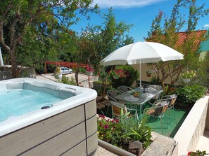 A hot tub with a table and chairs under a white umbrella, surrounded by greenery and a clear sky. - Holiday Home Sunrise - Three Bedroom Holiday Home (Omis)