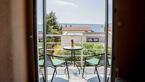 A balcony with two chairs and a table, overlooking a body of water and buildings. - Apartments Smokvica - Superior One Bed/ Apt (Starigrad)