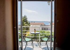 A balcony with two chairs and a table, overlooking a body of water and buildings. - Apartments Smokvica - Superior One Bed/ Apt (Starigrad)
