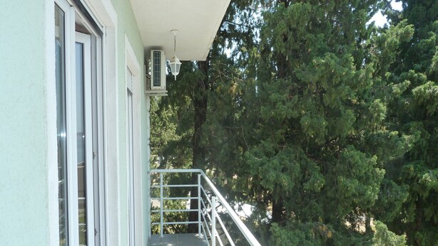 A balcony with a metal railing, a window with a view of trees, and a ceiling-mounted air conditioning unit. - Apartments Smokvica - Superior One Bed/ Apt (Starigrad)