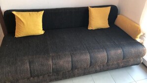 A dark-colored sofa with two yellow cushions against a plain wall. - Apartmani Villa Borzic - One Bedroom Apartment With Terarce and Sea View (Omis)