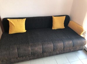 A dark-colored sofa with two yellow cushions against a plain wall. - Apartmani Villa Borzic - One Bedroom Apartment With Terarce and Sea View (Omis)