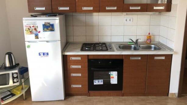 A compact kitchen with a white refrigerator, a stove, a sink, and wooden cabinets. - Apartmani Villa Borzic - One Bedroom Apartment With Terarce and Sea View (Omis)