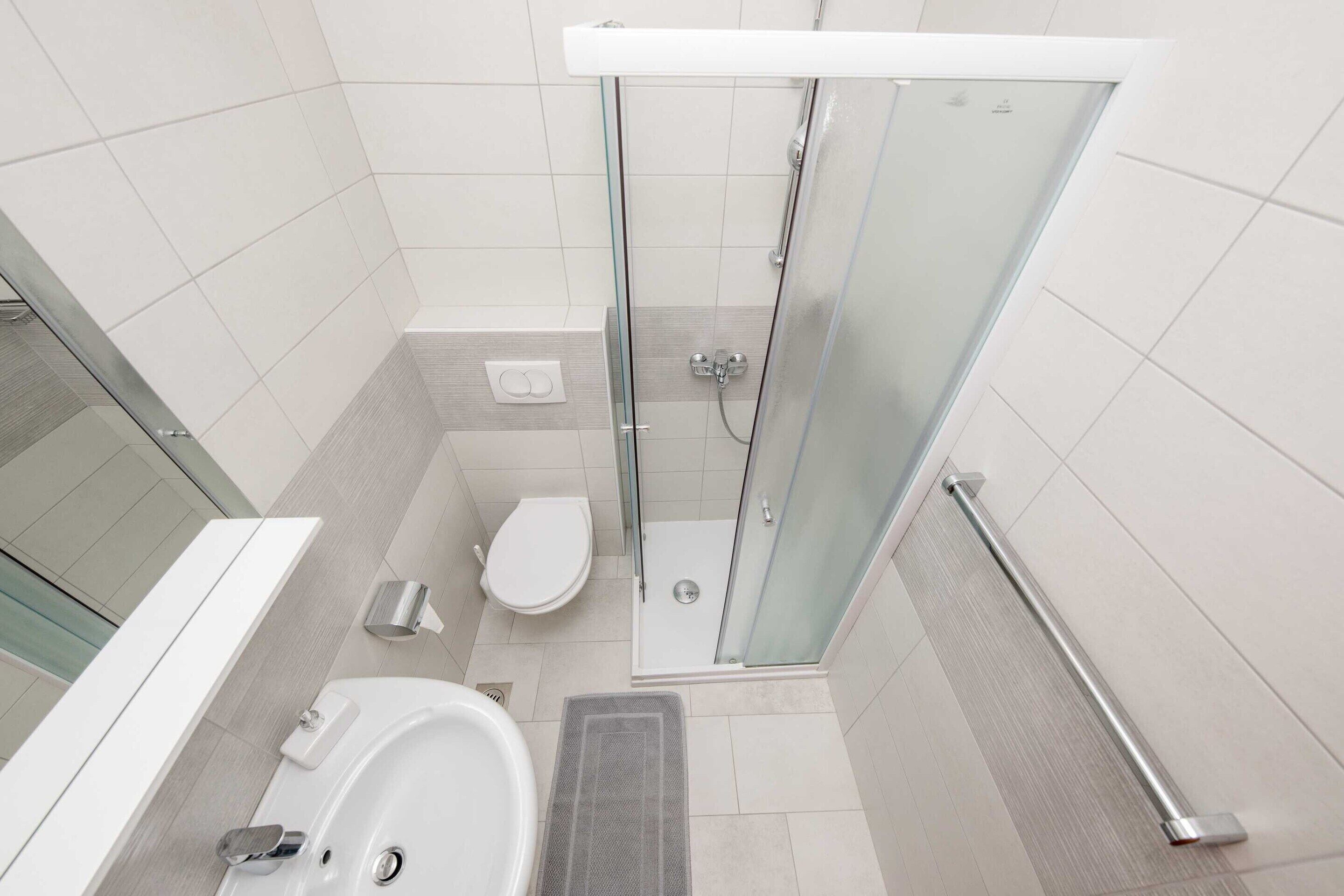 A modern bathroom with a glass-enclosed shower, a toilet, and a bathtub.