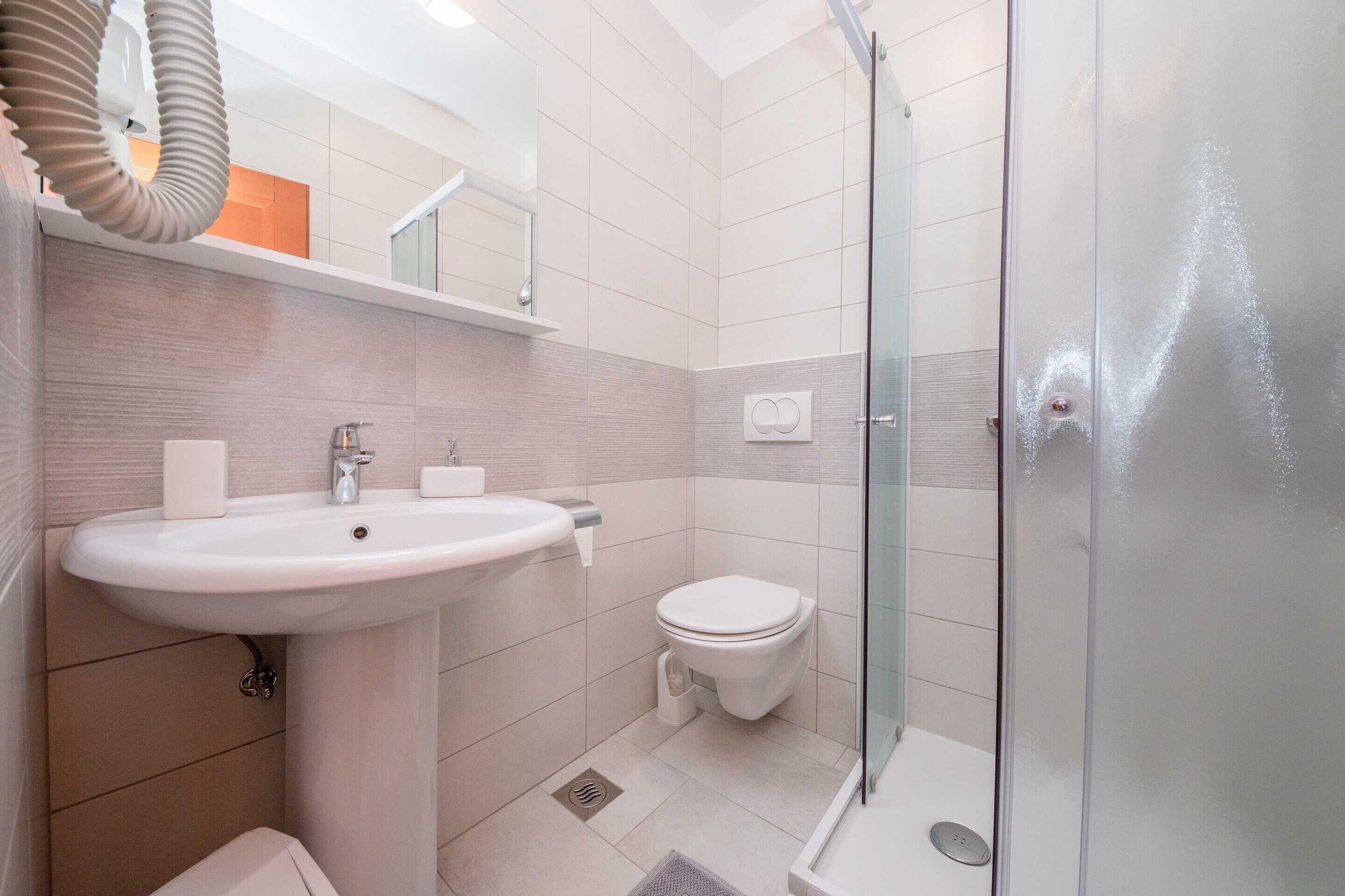 A modern bathroom with a sink, toilet, and glass shower enclosure.