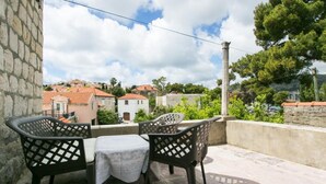 A balcony with two chairs and a table, overlooking a residential area with houses and trees. - Villa Marini Dvori - Two-bedroom Apartment With Terrace (Dubrovnik)