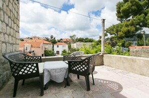 Ein Balkon mit zwei Stühlen und einem Tisch, der auf einen Wohnbereich mit Häusern und Bäumen blickt.