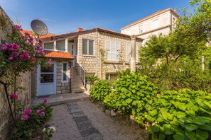 Ein Steinhaus mit Garten, Satellitenschüssel und einer Treppe, die zum Eingang führt.