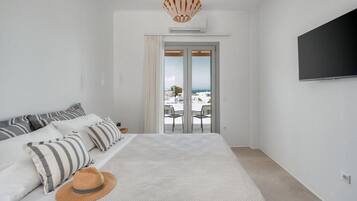 Une chambre à coucher avec un lit, une télévision et une vue sur l’extérieur, visible à travers une porte.