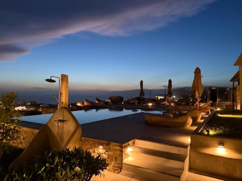A pool area with steps leading to the water, lounge chairs, and umbrellas.
