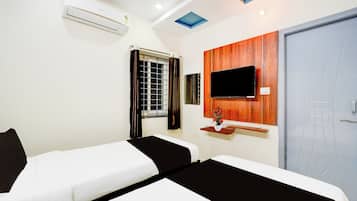 Une chambre d’hôtel avec deux lits, un téléviseur fixé au mur, une fenêtre avec des rideaux et un appareil de climatisation.