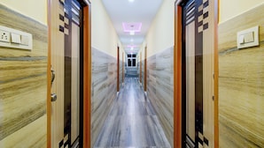 A hallway with marble flooring, wooden doors, and recessed ceiling lighting. - Super Collection O Khajaguda Hills (Hyderabad)