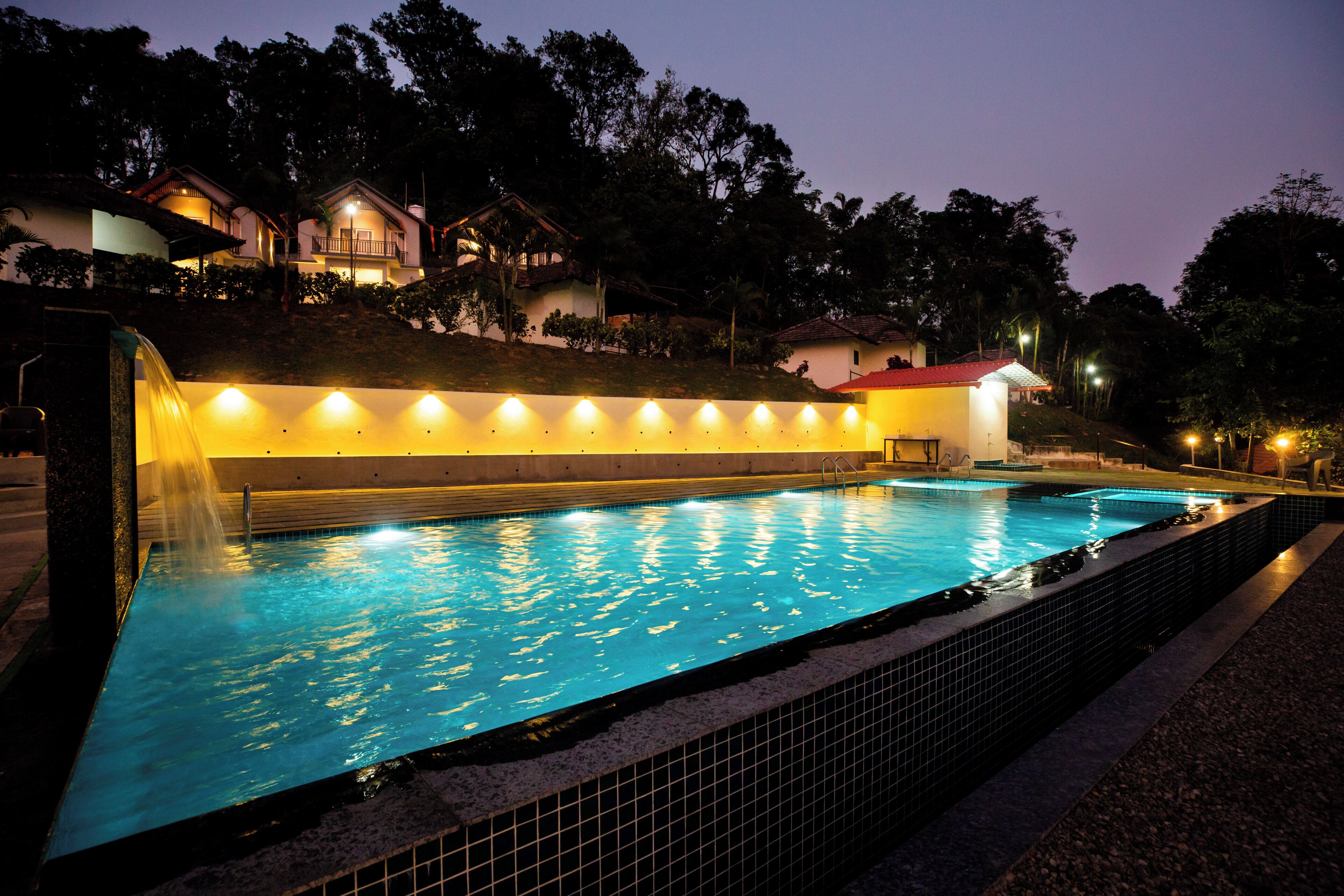 A swimming pool with a tiled edge, surrounded by a low wall with evenly spaced lights.