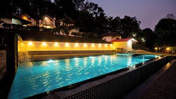 A swimming pool with a tiled edge, surrounded by a low wall with evenly spaced lights.