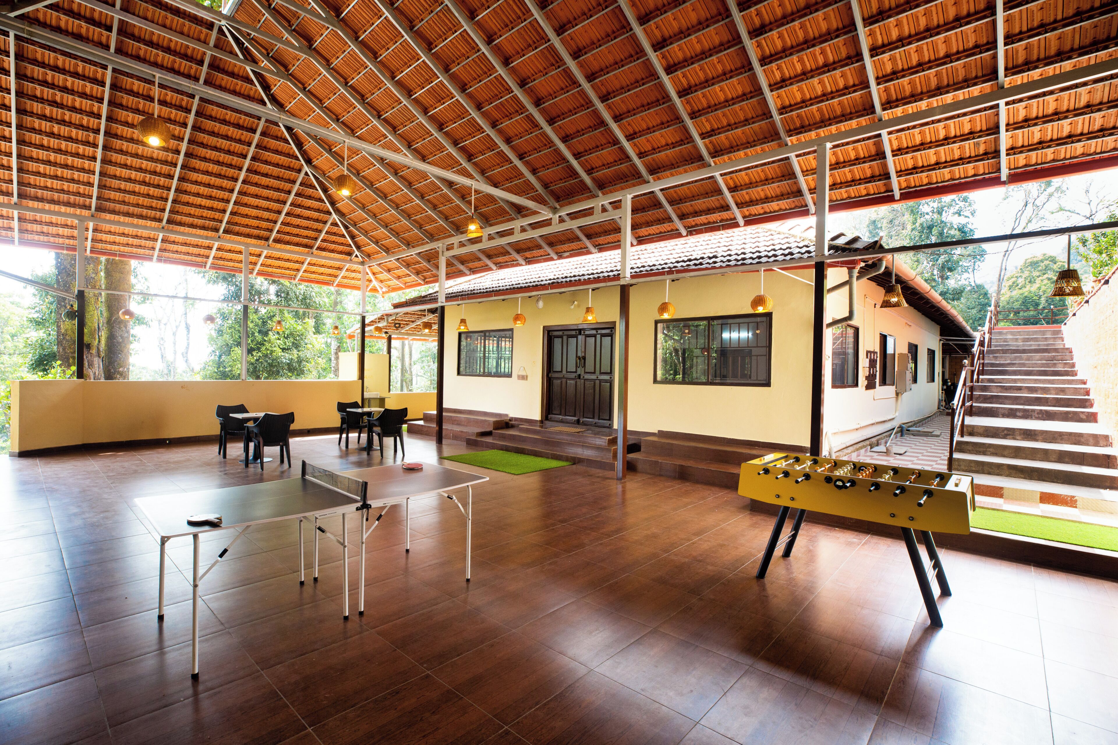 An indoor recreational area with a ping pong table, a foosball table, and a seating area with tables and chairs.