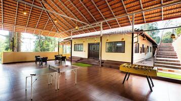 An indoor recreational area with a ping pong table, a foosball table, and a seating area with tables and chairs.
