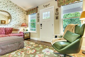 Ein Zimmer mit einem grünen Ledersessel, einem gemusterten Sofa und einem floralen Teppich.