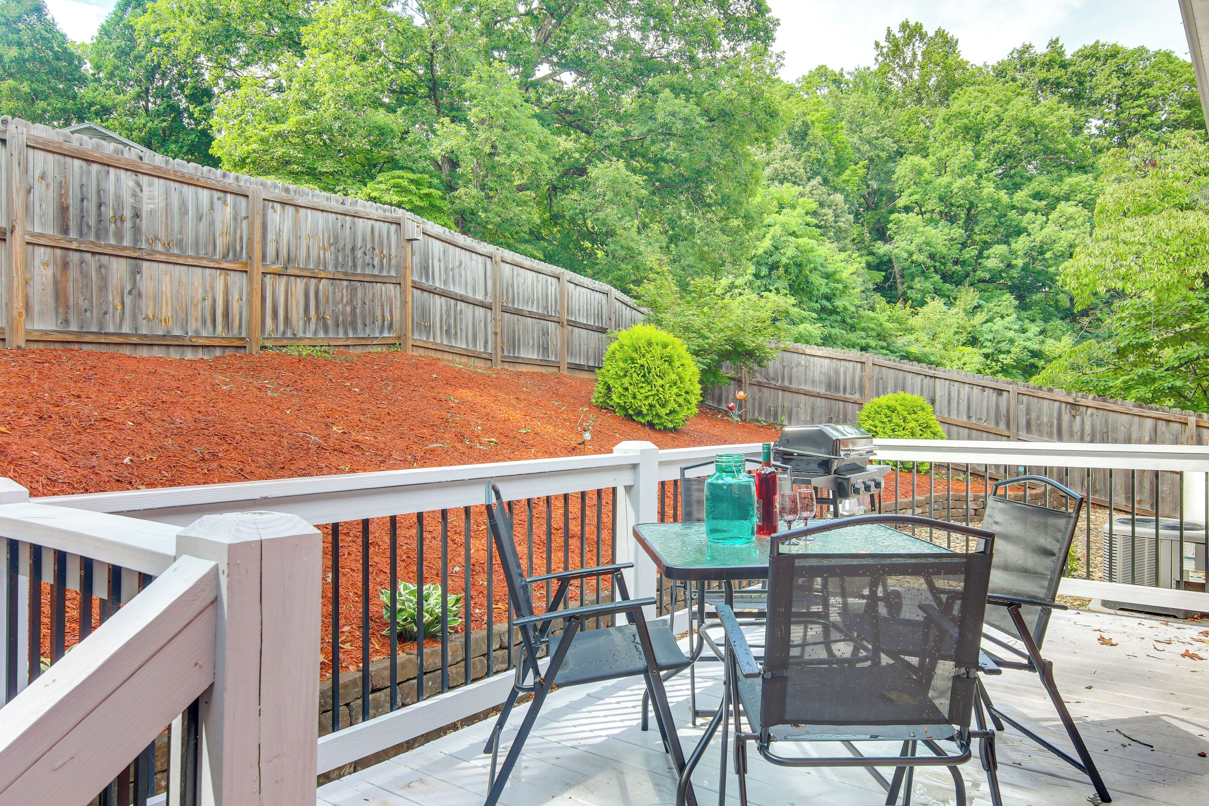 A patio with a table and chairs, a barbecue grill, and a wooden fence.