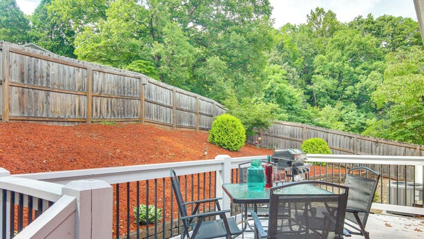 A patio with a table and chairs, a barbecue grill, and a wooden fence. - Walk to Waynesville Hot Spots! 'Woodland Cottage' (Waynesville)