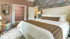 A bedroom with a bed, a nightstand, a lamp, a mirror, and a door. - Walk to Waynesville Hot Spots! 'Woodland Cottage' (Waynesville)