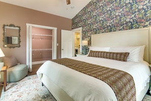 Ein Schlafzimmer mit Bett, Nachttisch, Lampe, Spiegel und Tür.