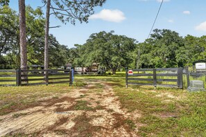 A gated property with a dirt path leading to a building, surrounded by trees and a fence. - 6 Mi to Rainbow Springs! Home w/ Outdoor Space (Ocala)