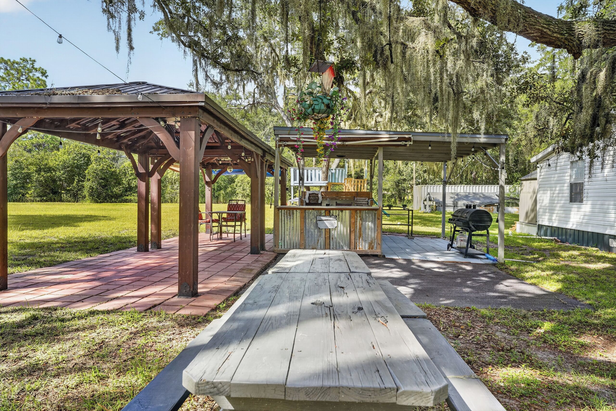Un'area patio all'aperto con una pergola in legno, un tavolo da picnic e un barbecue.