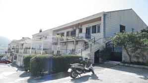 Ein Gebäude mit einer Treppe, die zu einem Balkon führt, einem abgestellten Roller und einem Schild mit der Aufschrift Zimmer und einer Kamera.