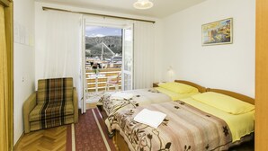 Ein Hotelzimmer mit Bett, Stuhl, Tisch und Blick auf eine Brücke und Berge.