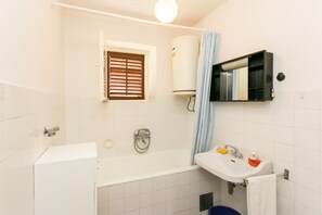 A bathroom with a bathtub, a sink, a window with blinds, a towel rack, and a toilet. - Guest House Bridge View - Studio With Balcony and Sea View (Dubrovnik)