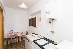 A compact kitchen with a dining table, chairs, a stove, a sink, and a hanging light fixture. - Guest House Bridge View - Studio With Balcony and Sea View (Dubrovnik)
