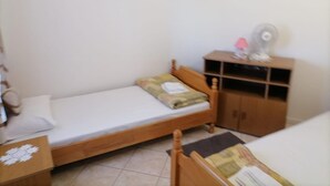 A small, single-bed room with a wooden headboard, a bedside table, a small cabinet, and a wall-mounted fan. - Apartments Libertas - One Bedroom Apartment With Terrace and Sea View- (Rogoznica)
