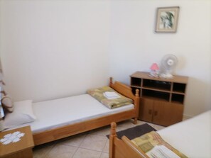 A small, single-bed room with a wooden headboard, a bedside table, a small cabinet, and a wall-mounted fan. - Apartments Libertas - One Bedroom Apartment With Terrace and Sea View- (Rogoznica)
