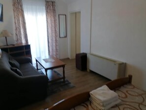 A living room with a sofa, a coffee table, a radiator, and a door. - Apartments Libertas - One Bedroom Apartment With Terrace and Sea View- (Rogoznica)